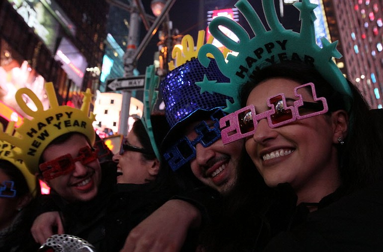 A group of friends pose for photographs as they take part in the New Year's Eve festivities in New York's Times Square Friday.