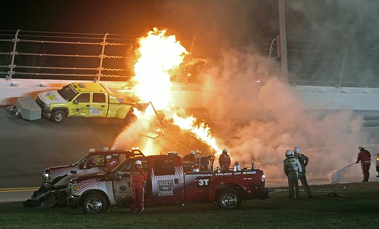 Emergency workers try to put out a fire after Juan Pablo Montoya's car struck the truck during the NASCAR Daytona 500 auto race at Daytona International Speedway in Daytona Beach, Fla., Monday.