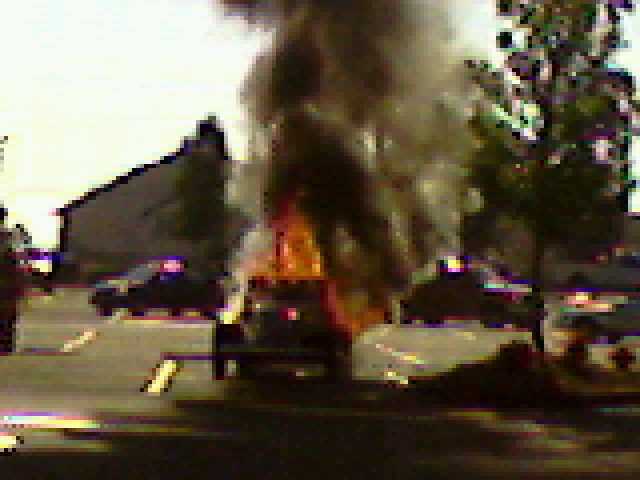 A woman stopped at a red light snapped a cell phone picture of a nearby car after it went up in flames.