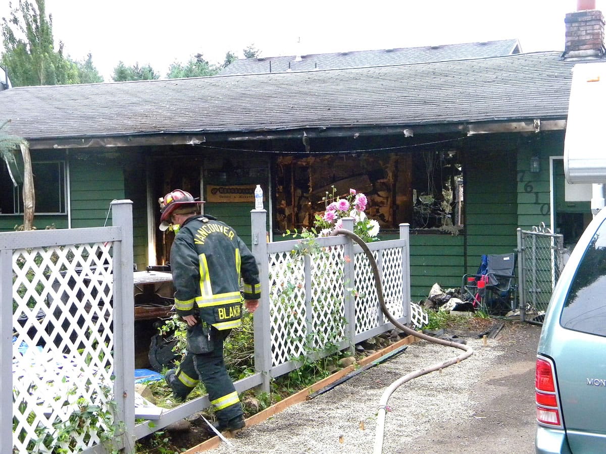 Firefighters extinguish flames early in the morning Aug. 6, 2014 at a house fire at 7610 N.E.