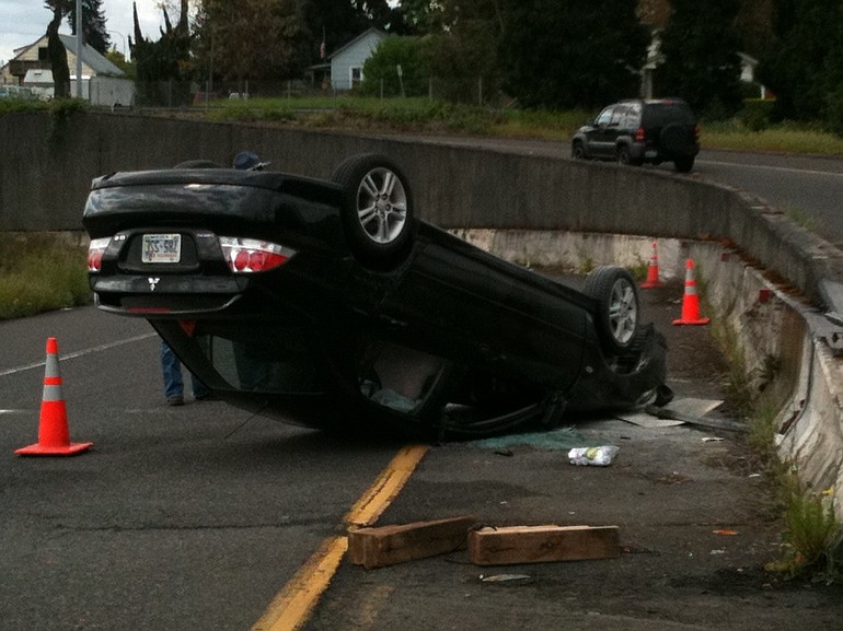 A late-model Mitsubishi sedan lies on its top on the 39th Street offramp from southbound Interstate 5.