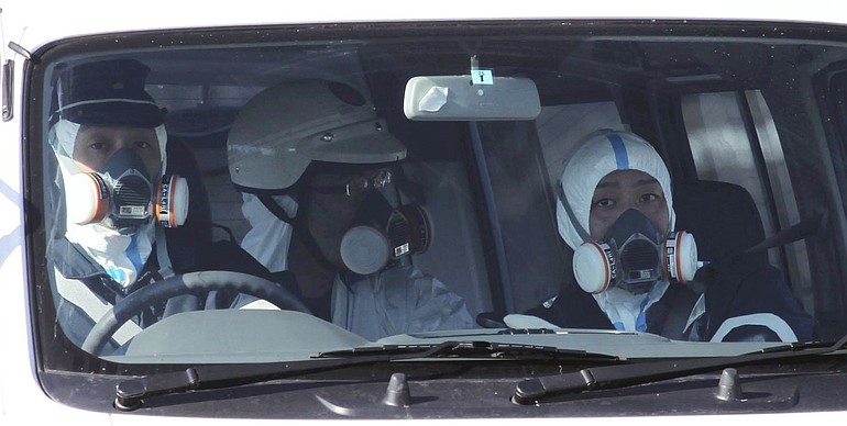 Police officers wearing gas masks patrol in the area of the Fukushima power plant's Unit 1 in Okumamachi, Fukushima Prefecture (state), northern Japan, Saturday, March 12, 2011, amid fears that a part of the plant could meltdown after being hit by a powerful earthquake and tsunami Friday.