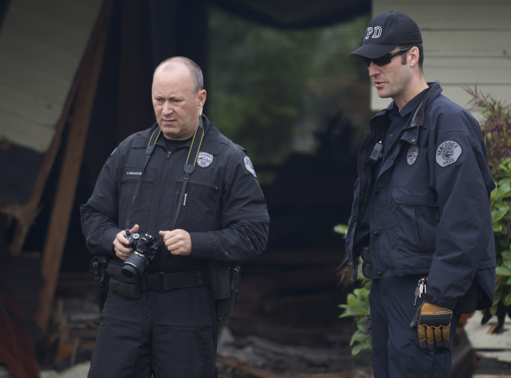 Dustin Goudschaal, right, and Paul Brewster of the Vancouver Police Department inspect a car that ran into an east Vancouver house on June 14.