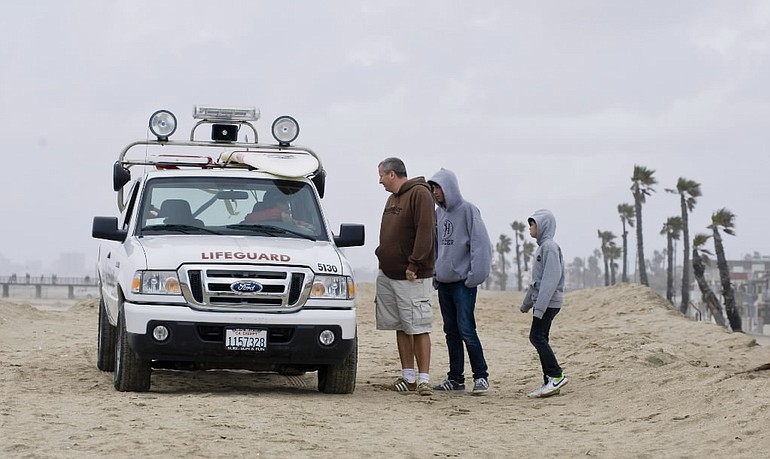 A lifeguard stops to tell a group of people that Southern California's Seal Beach is closed for safety reasons after the earthquake in Chile and the possible tsunami surge along the West Coast on Saturday.