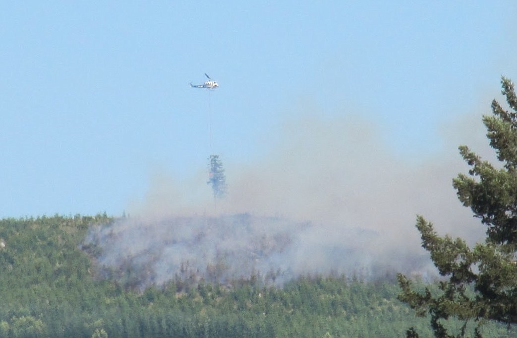 A helicopter makes a water drop on a wildfire burning Friday evening near the East Fork Lewis River near the mouth of Dole Valley in northeast Clark County.