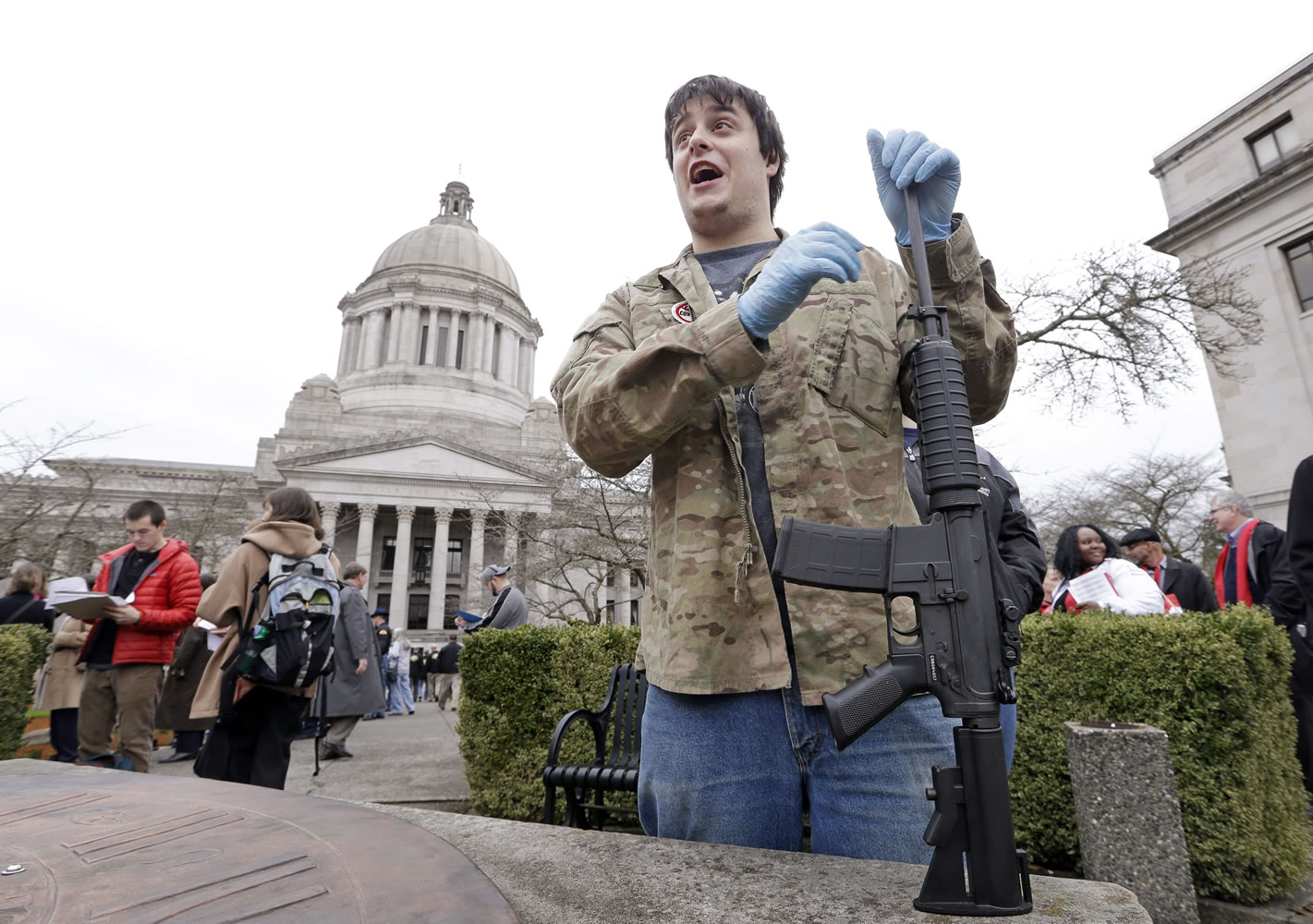 Devyn Hembry leans on his Bushmaster rifle as he waits to get in line to enter a House panel hearing on an initiative to expand firearm background checks in the state on Jan. 28 in Olympia.