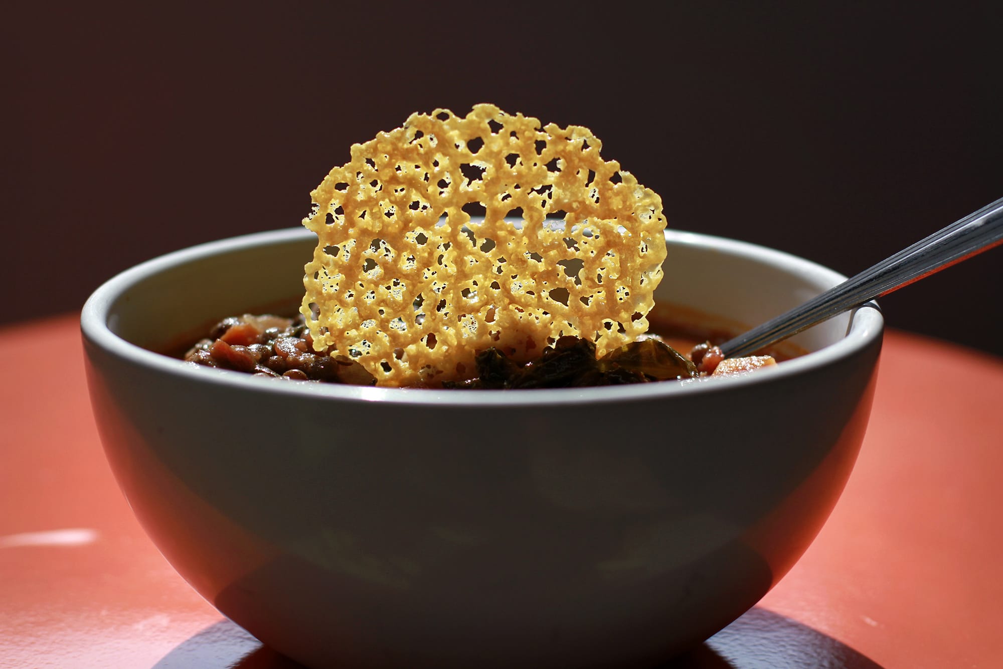 A cheddar crisp bedecking lentil soup