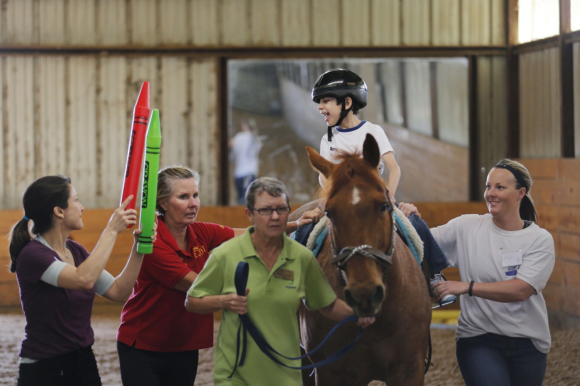 Jonathan Lopez, 7, who has cerebral palsy, watches therapist Kristi Immitt, far left, while volunteers guide Patron during the boy's hippotherapy session at Equest on March 31.