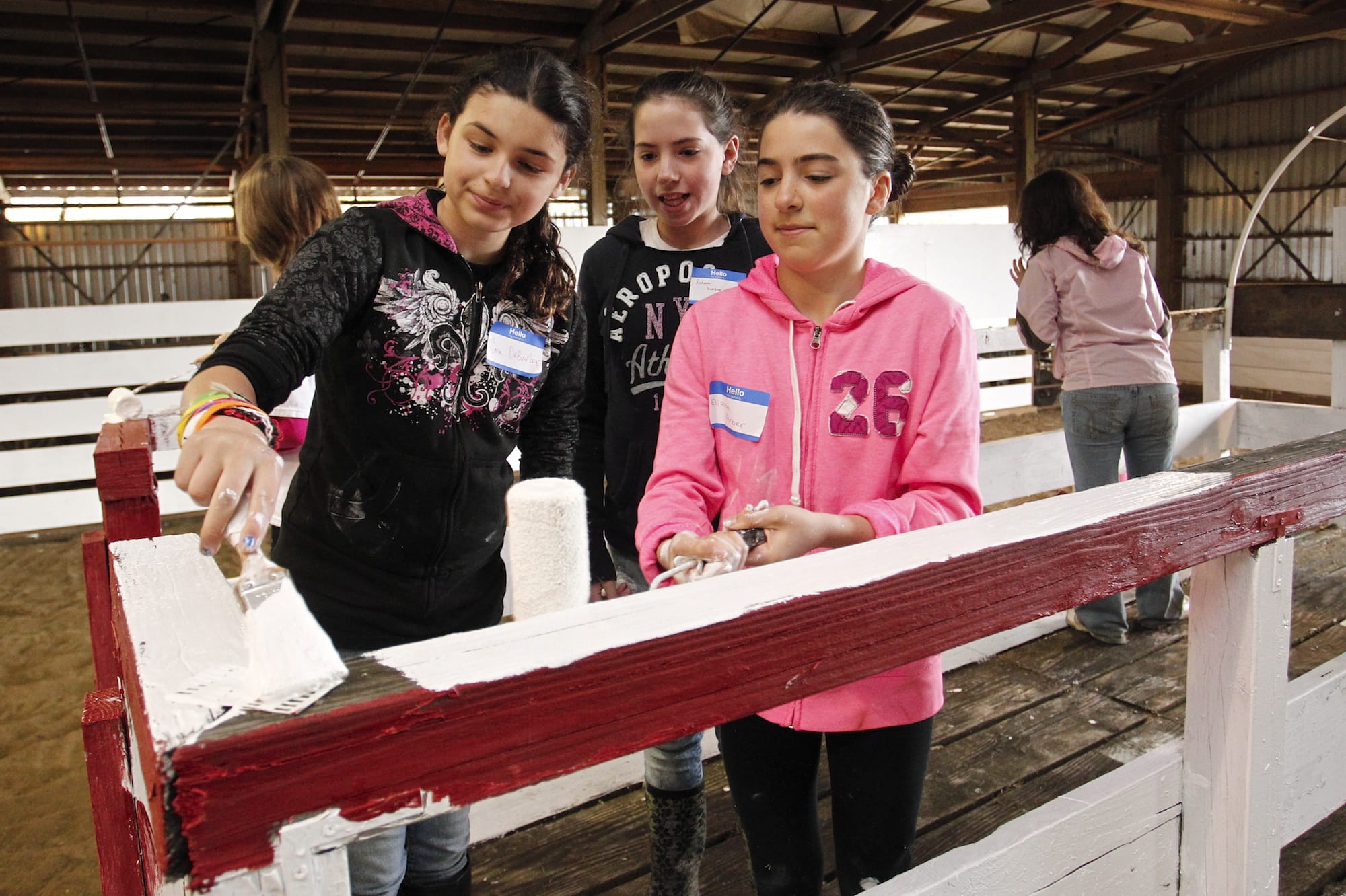 Cora DeBarber, from left, Rebecca Hembree and Eliana Farber from Vancouver School of Arts and Academics paint the walls and fences at Silver Buckle Ranch in Brush Prairie as part of the Day of Caring project.