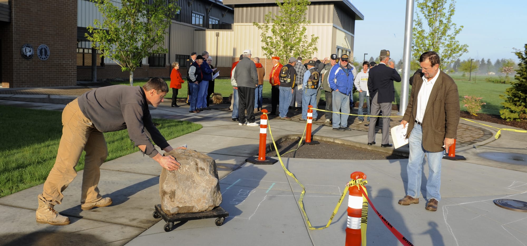 Alek Igumnov, left, is directed by Kelly Punteney, right, as he moves the stone into position.