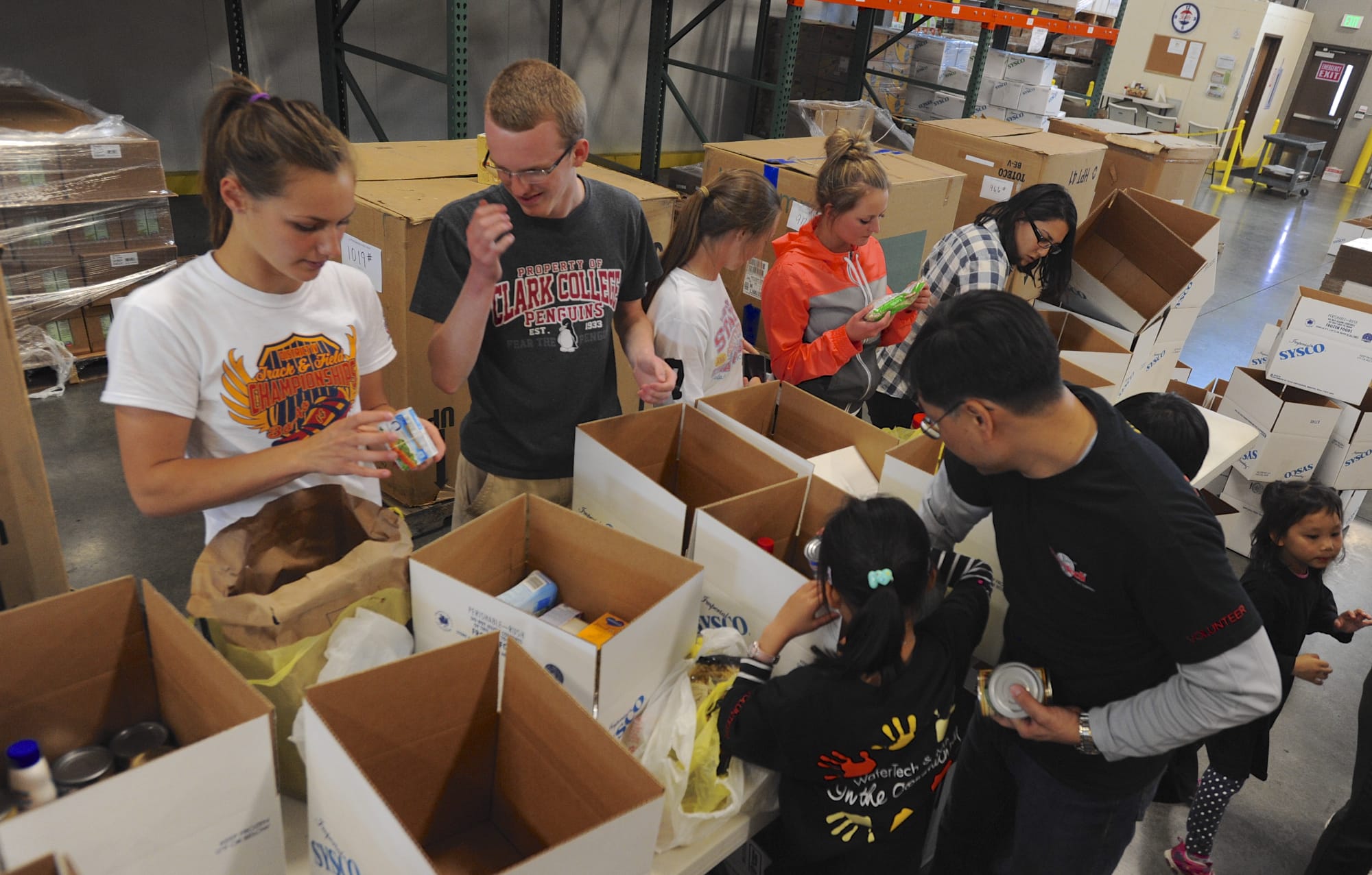 Volunteers, from left, Ellery Roberts, Michael Hall, Jennifer Ross, Megan Wilson and Esther Pisano sort food donations at a regular Tuesday night repack event at the Clark County Food Bank.