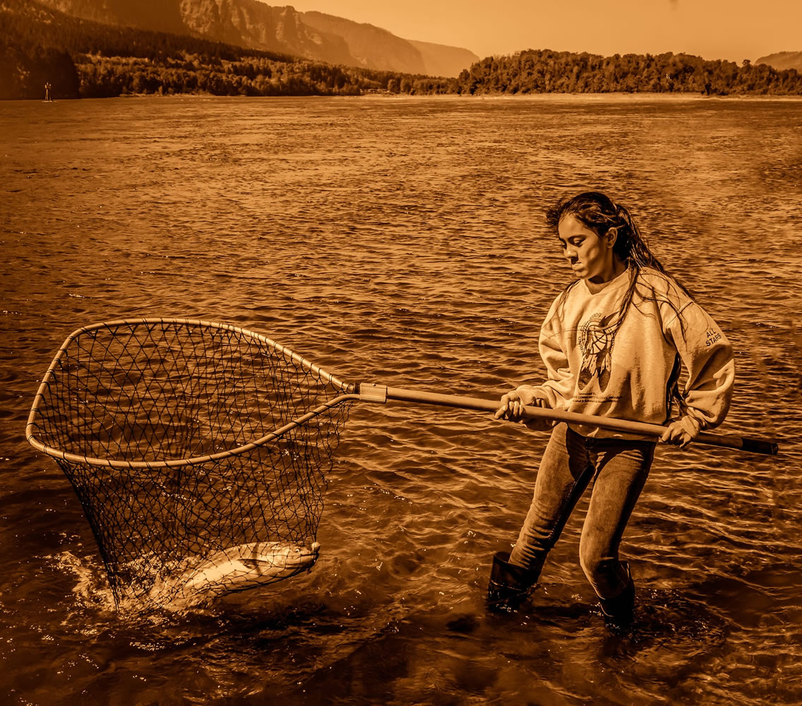 A young member of The Confederated Tribes of Warm Springs helps to land a salmon caught by her younger brother.