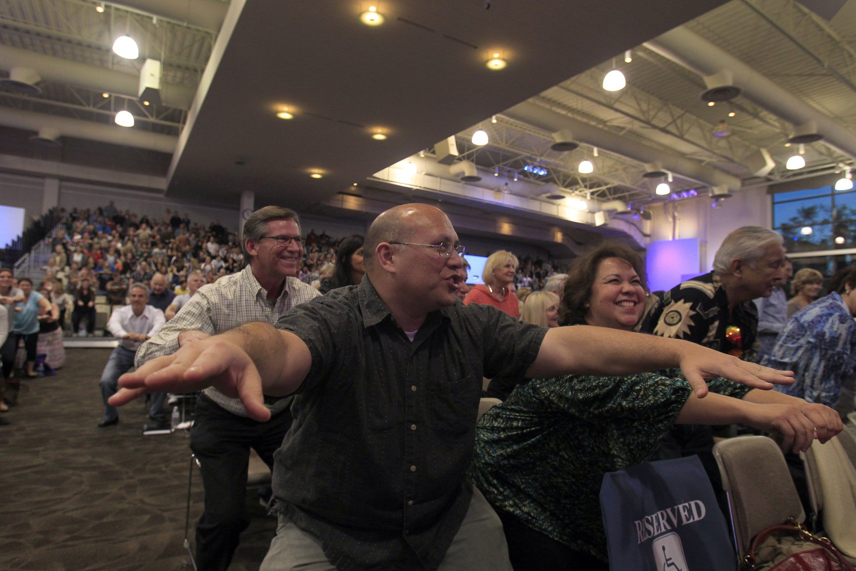 Congregation members exercise in their seats during a rally for pastor Rick Warrenu2019s u201cDaniel Planu201d at Saddleback Church in Lake Forest, Calif.