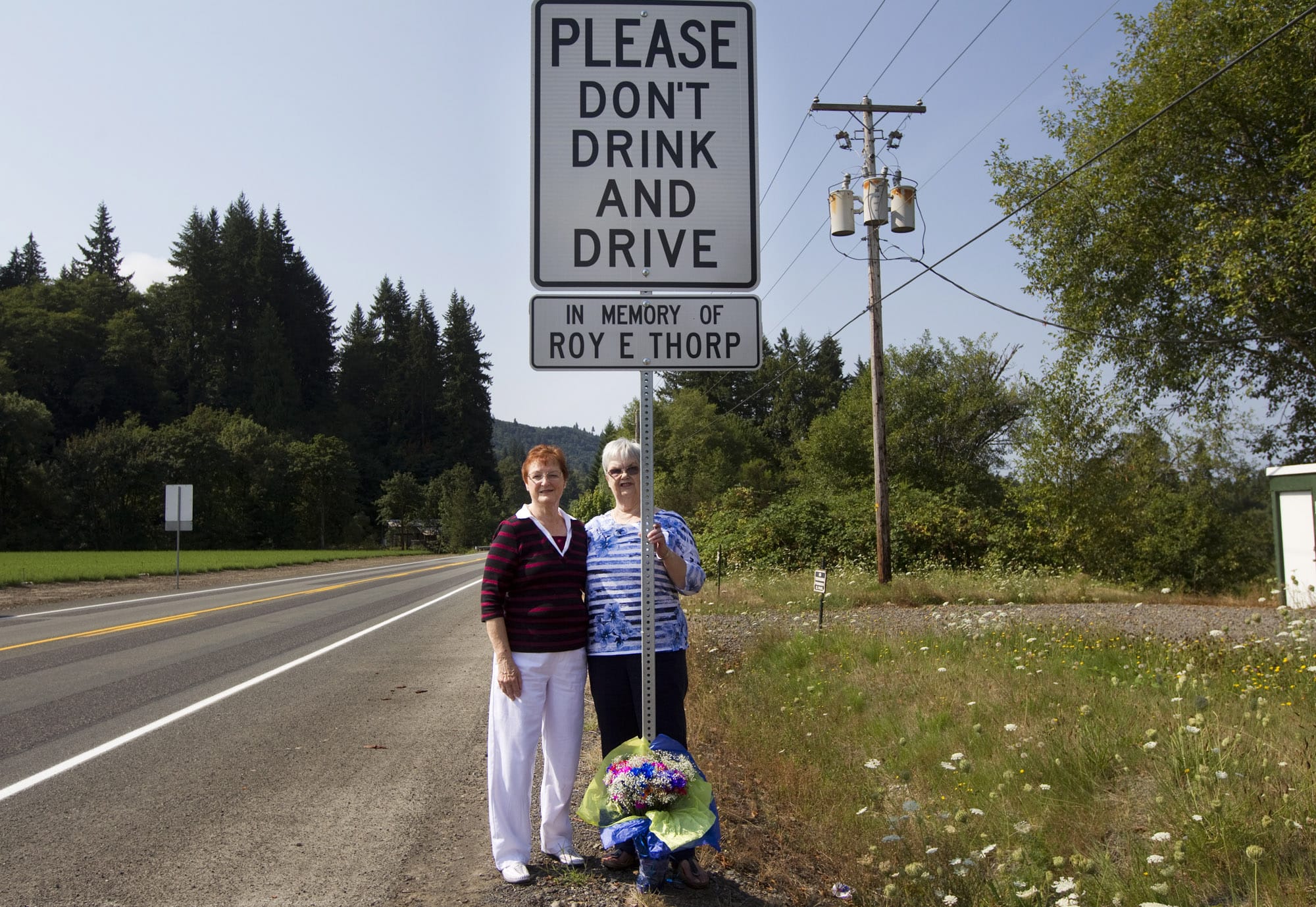 Connie Jones, left, and Marlys Thorp stand by a memorial sign dedicated to Roy Thorp, a 76-year-old Vancouver man who was killed three years ago by a speeding drunken driver on Northwest Hayes Road in Woodland.
