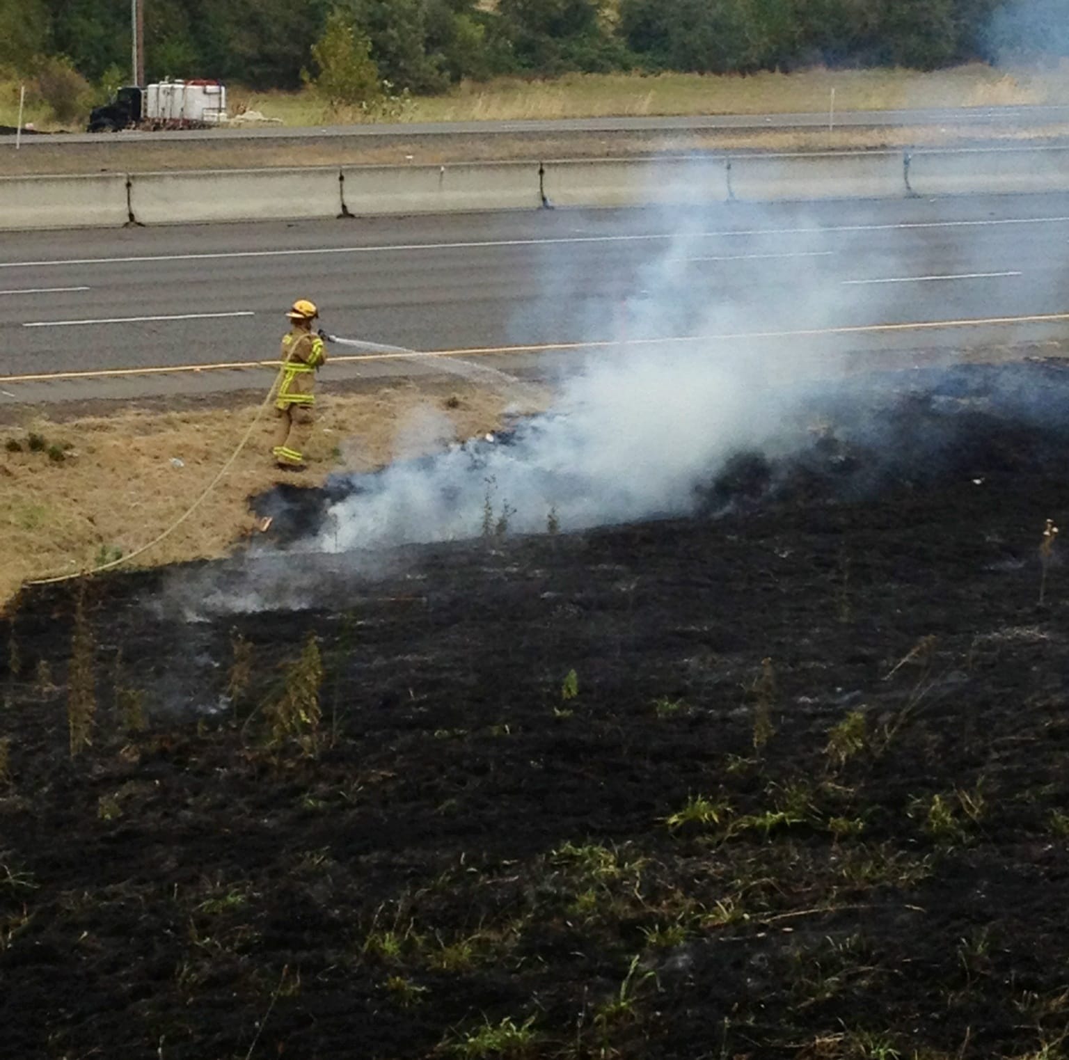 Firefighters extinguish a brush fire in the median of Interstate 5 south of Ridgefield.