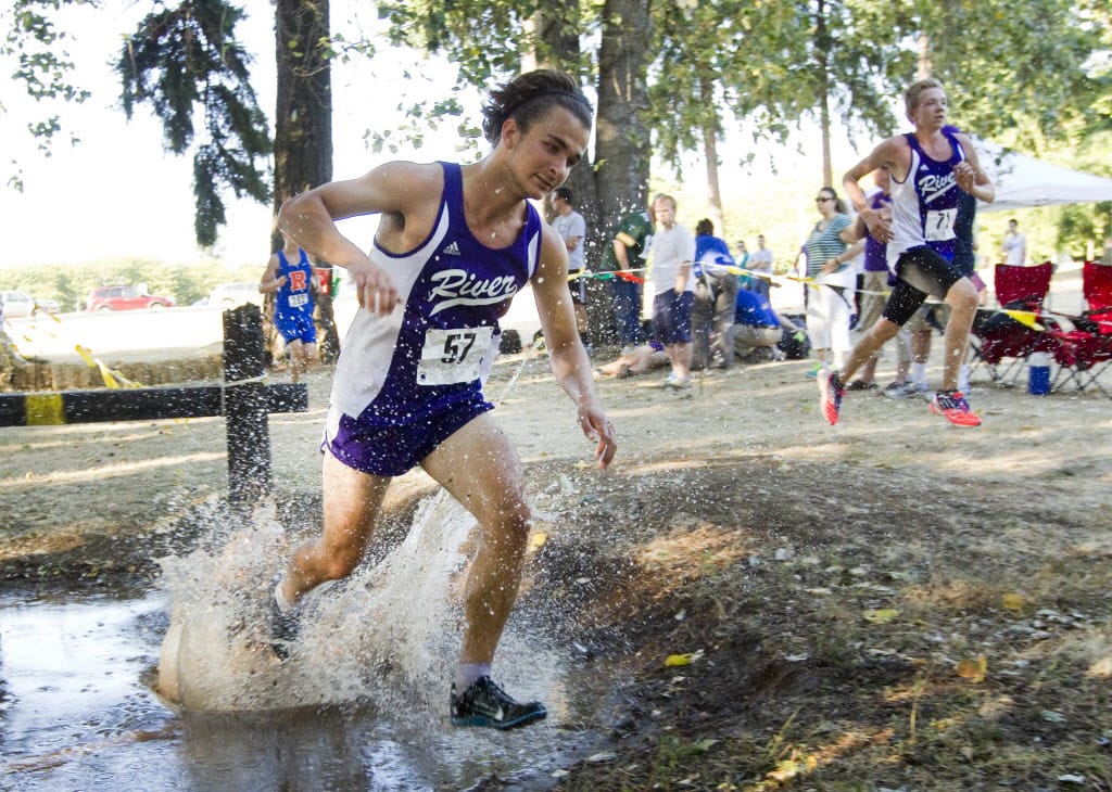 Ryan Boe of Coulmbia River High school takes a splash in a puddle as he runs in the men's varsity cross country race at Hudson's Bay High School's Run-A-Ree in Vancouver Friday September 12, 2014.
