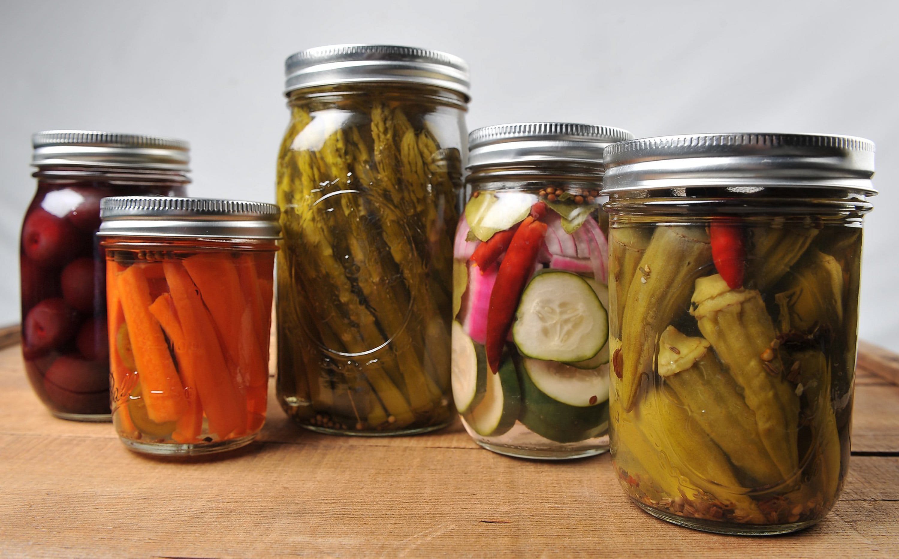 Jars of colorful pickled produce, including, from left, pickled cherries (Kristy Page), carrots (Kristy Page), asparagus (Felix Muzquiz), cucumbers (Kristy Page) and okra (Felix Muzquiz).
