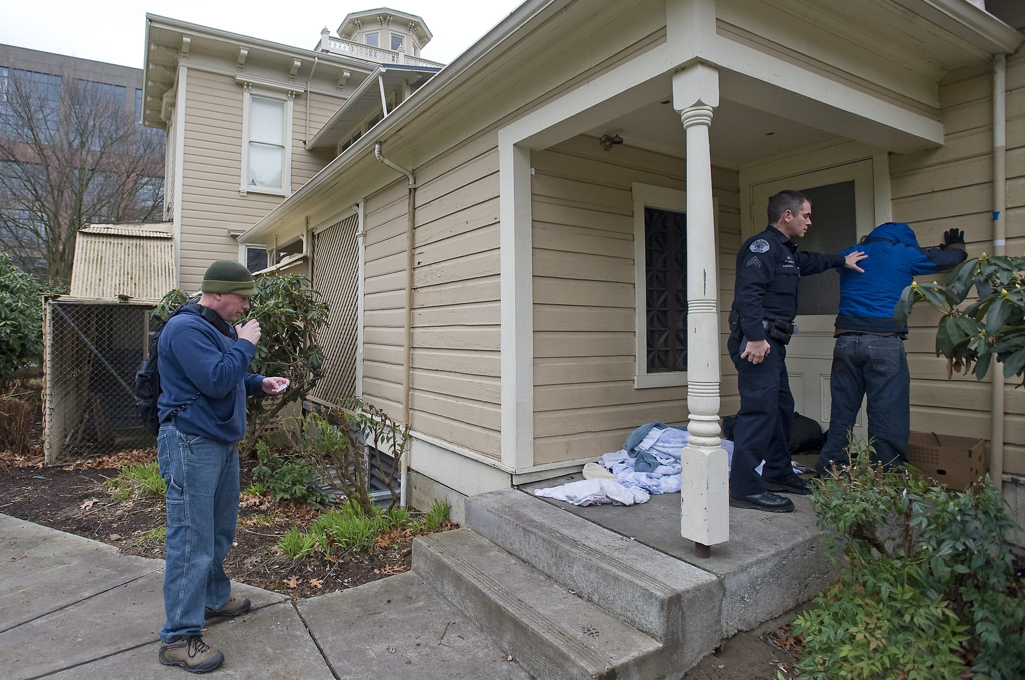 Vancouver Police Cpl. Drue Russell, left, runs a man's identification that he found camping next to the Slocum House in Esther Short Park while VPD Cpl. Duane Boynton secures the man after he disclosed to officers that he was carrying a knife, as part of an ongoing effort by authorities to make the park a safer place on Friday March 4, 2011.