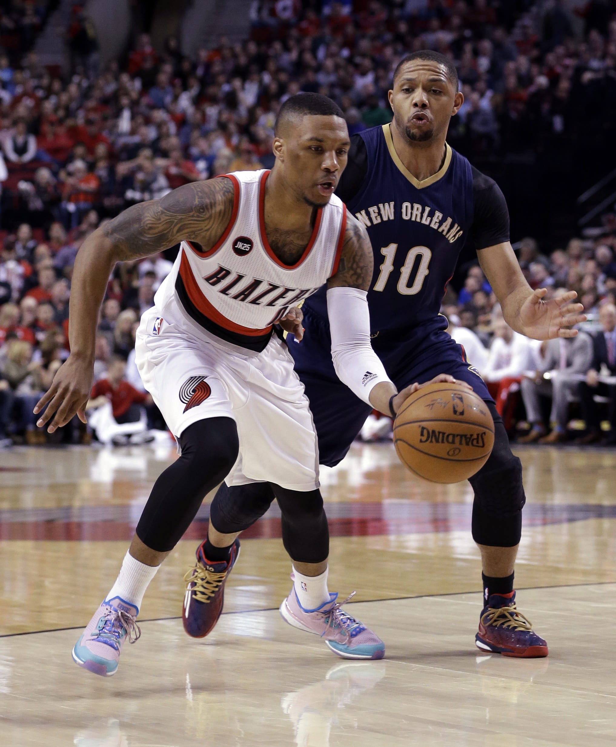 Portland Trail Blazers guard Damian Lillard, left, drives past New Orleans Pelicans guard Eric Gordon during the first half of an NBA basketball game in Portland, Ore., Saturday, April 4, 2015.
