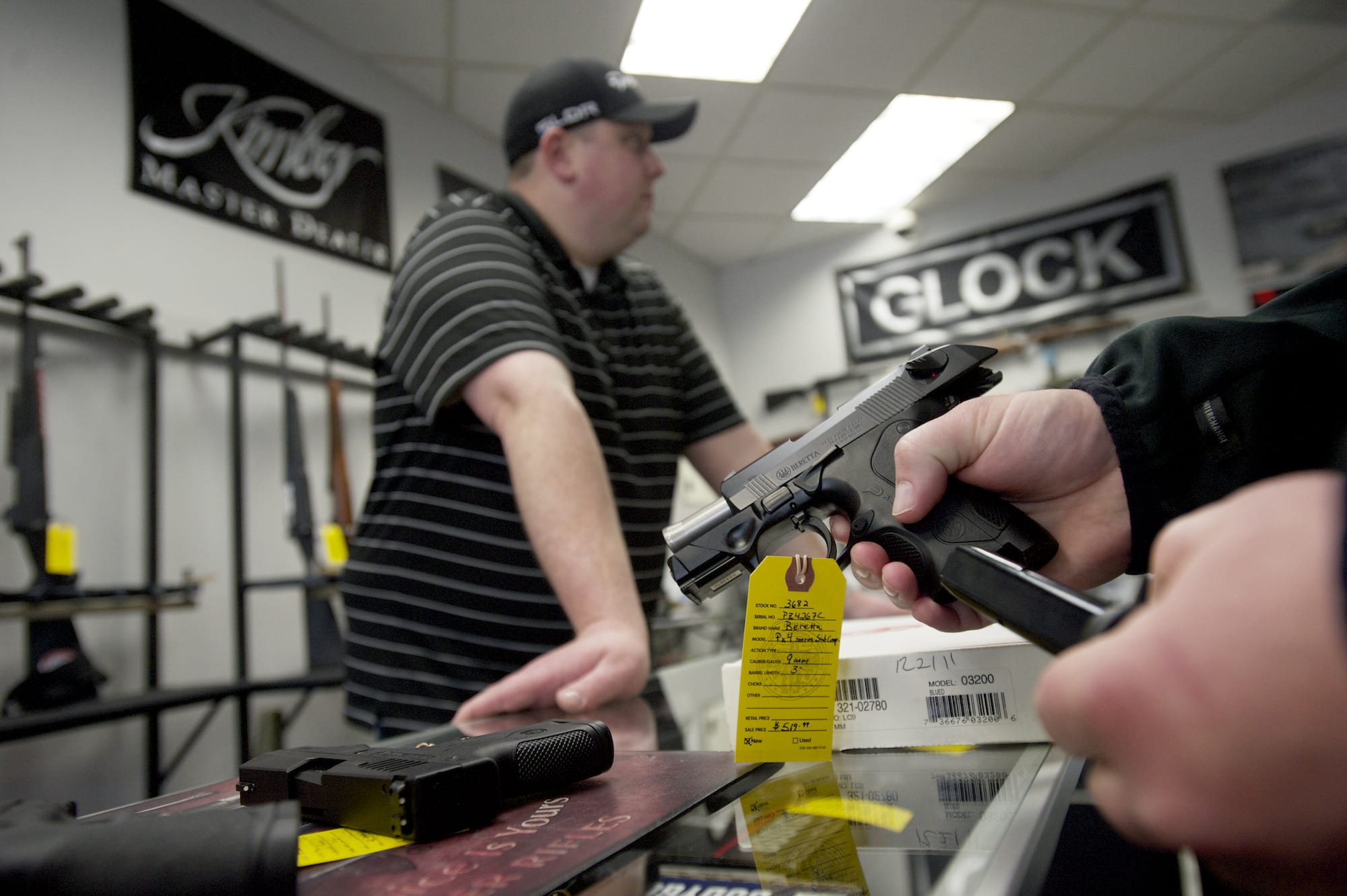 Brightwater Ventures Firearm Sales owner Nick Pratka waits as a customer looks at handguns.