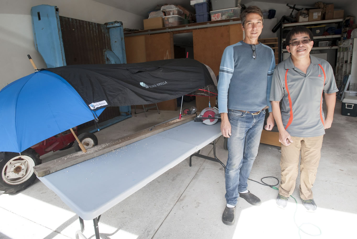 Chris Gibbons and Kevin Chong stand in front of one of their Slikr-Brellas at Gibbons’ home in Vancouver. The men displayed their procut, a poncho that hooks over umbrellas to create a tent that can be used on the sidelines of sporting events, at the recent Wak, Roll ‘n Run event in Portland, a fundraiser for United Cerebral Palsy of Oregon. They plan to put any profits from the sale of their product into a new non-profit to help disabled people learn about finance and business basics.