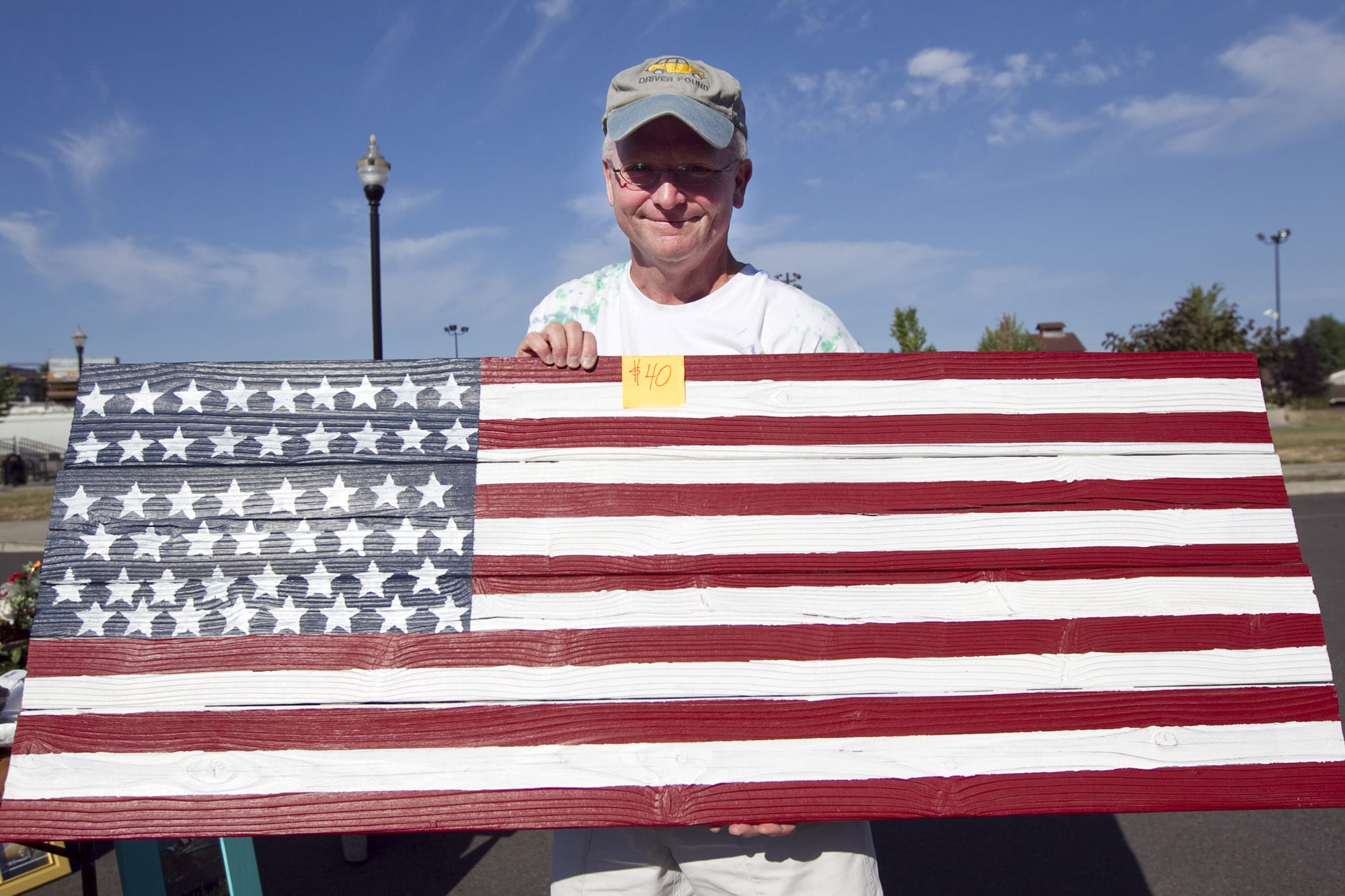 Army veteran Philip Johnson sells an American flag wall hanging he made from reclaimed cedar at a flea market to raise funds to build a veterans memorial in Battle Ground.