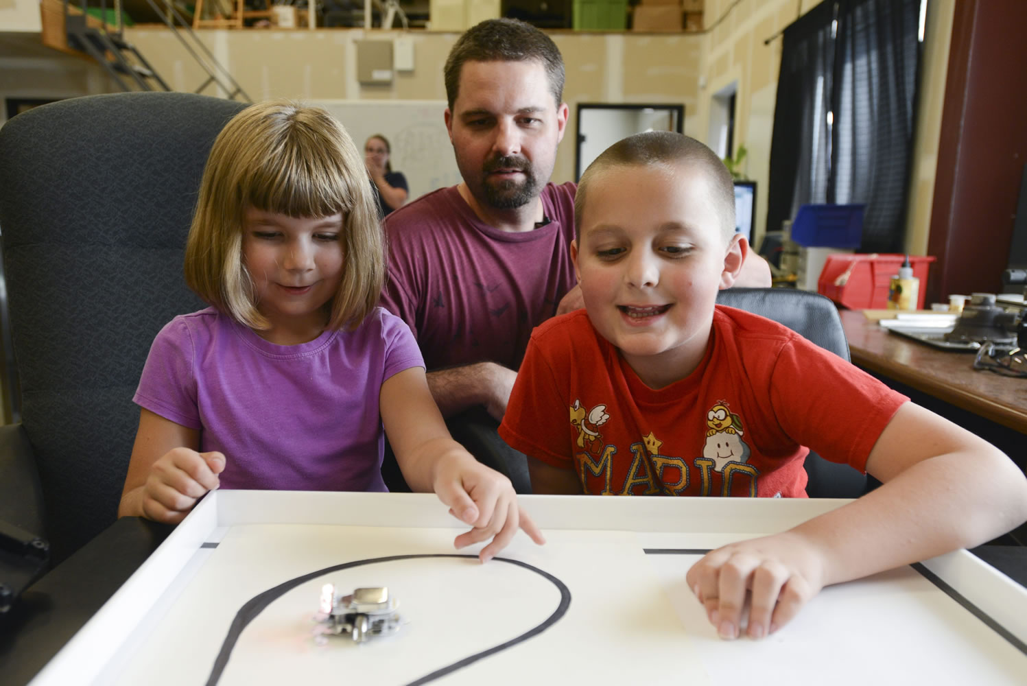 Siblings Hailey and Parker King play with Ringo, a robotic toy they helped design with their dad, Kevin King, center, on Thursday. Kevin King recently raised more than $80,000 on Kickstarter to start manufacturing and selling the robotic toys out of their Vancouver workshop.