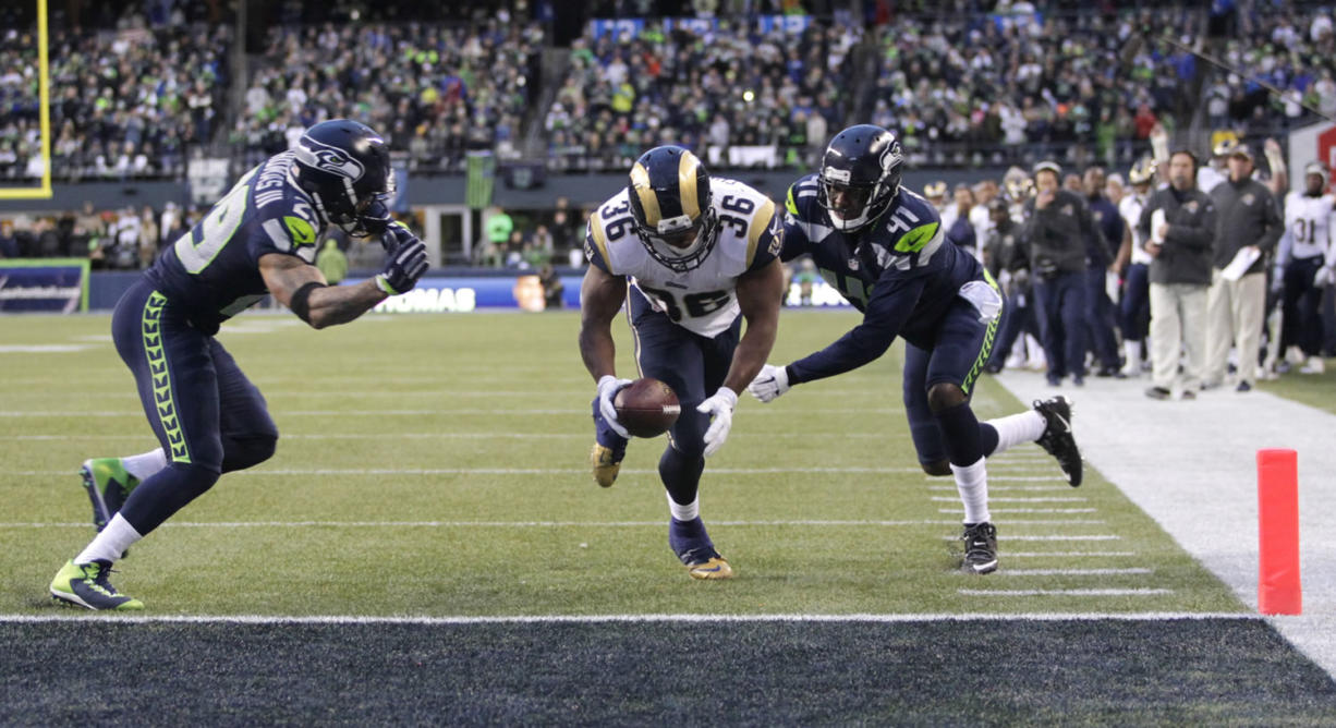 St. Louis Rams running back Benjamin Cunningham (36) is about to fumble in the end zone after a hit on the arm from Earl Thomas, left.