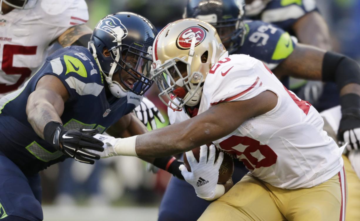 Seattle Seahawks' Bobby Wagner, left, closes in on San Francisco 49ers' Carlos Hyde, right, in the second half Sunday, Dec. 14, 2014, in Seattle.