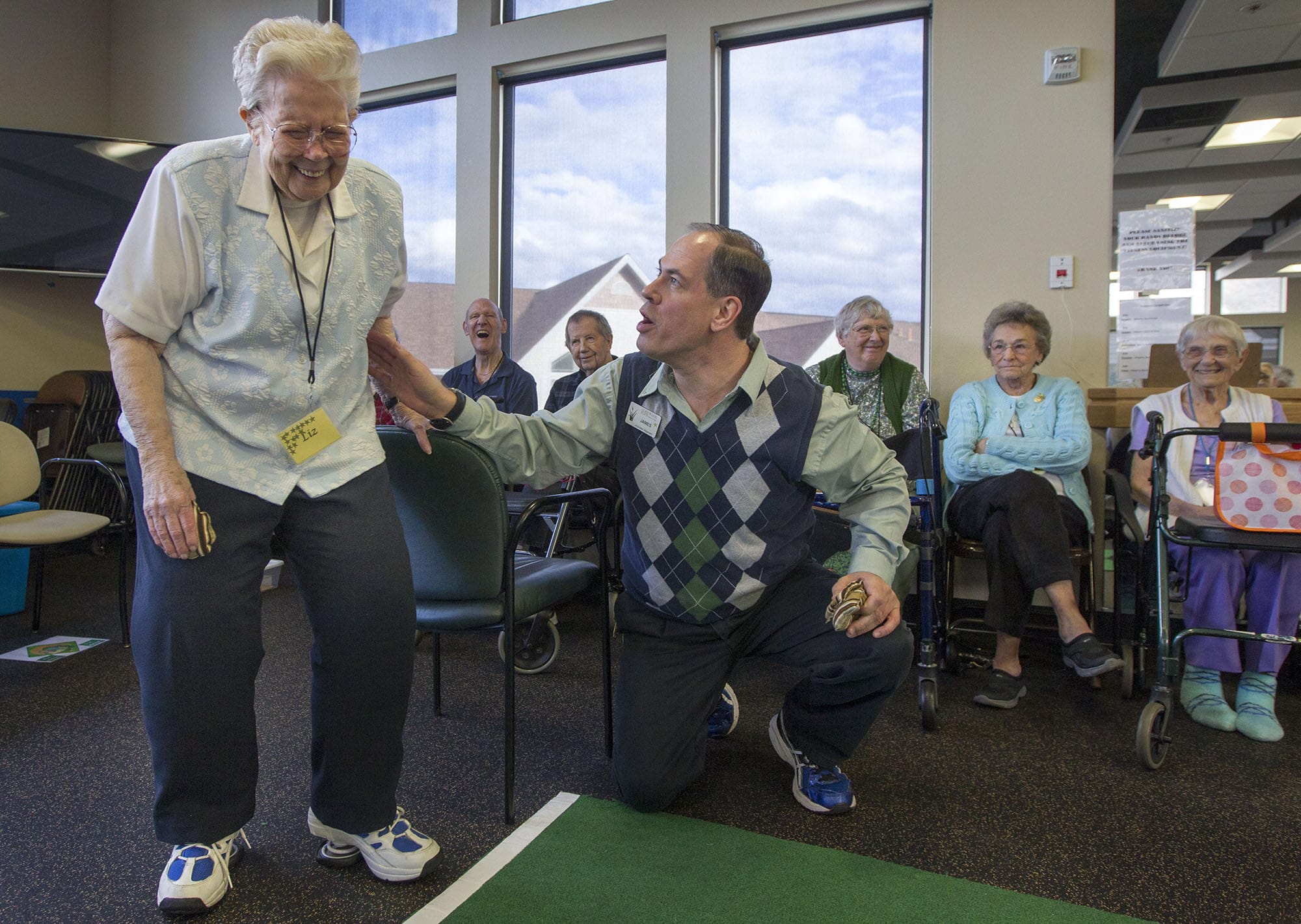 James Winther helps Liz Boss take aim as he leads teams of seniors in a game of bean bag baseball at Glenwood Place Senior Living in Vancouver earlier this month.