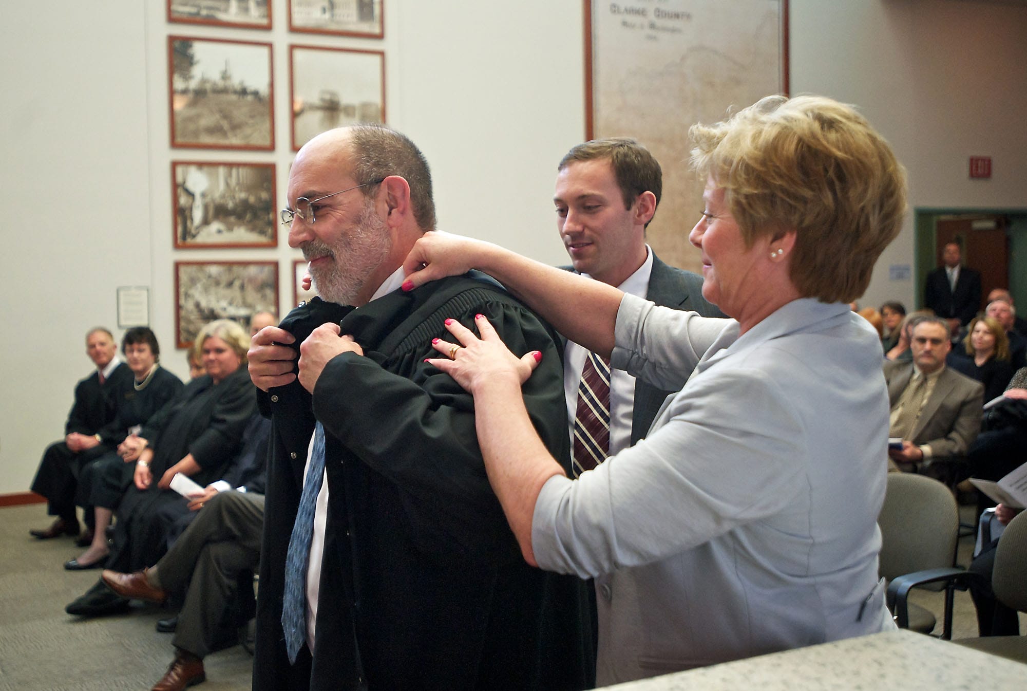 Rich Melnick gets help with his robe on Wednesday from his wife, Lori, and son, Ben, after he was ceremonially sworn in as a judge of the Washington state Court of Appeals Division 2.