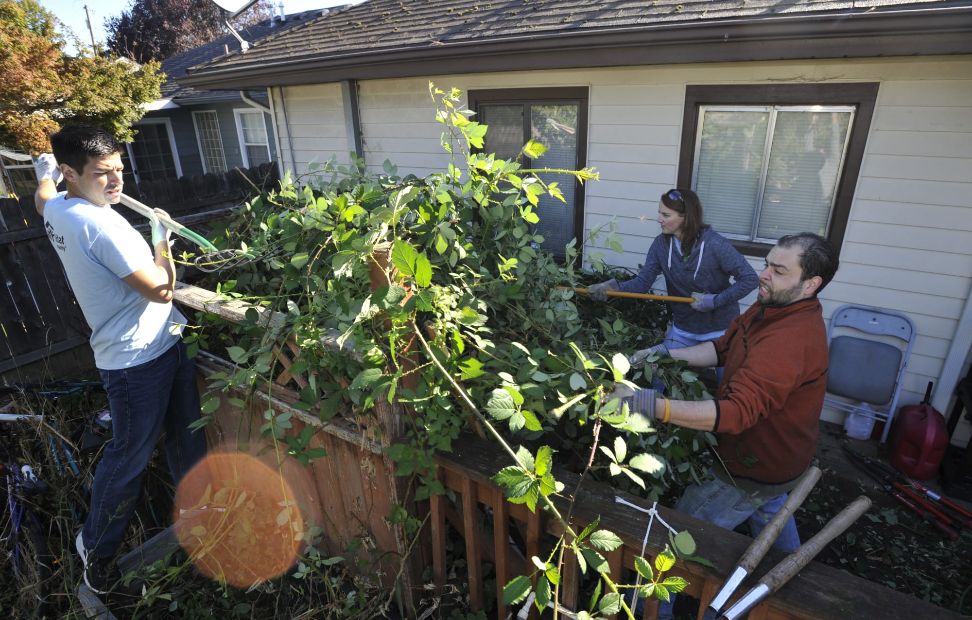 Jesse Lancaster, left, Jennifer Amsler and Andrew Swan remove blackberries Saturday as part of a volunteer effort through Evergreen Habitat for Humanity that focused on low-income homes in the Fruit Valley neighborhood.