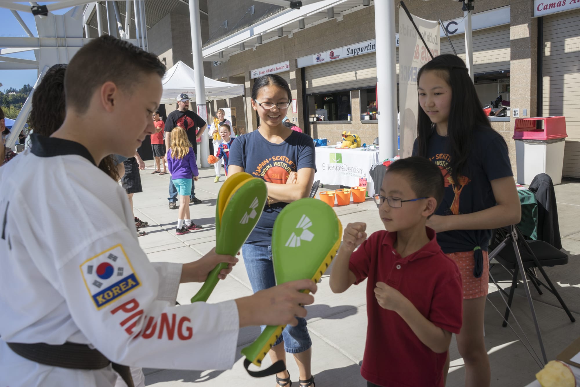 Nathan Chiu, 7, front center, learns about martial arts from Lanedon Wells, 13, of World Class Martial Arts while his sisters, Katie, back left, and Melodie watch at a health fair at Doc Harris Stadium on Saturday, Sept. 19, 2015.