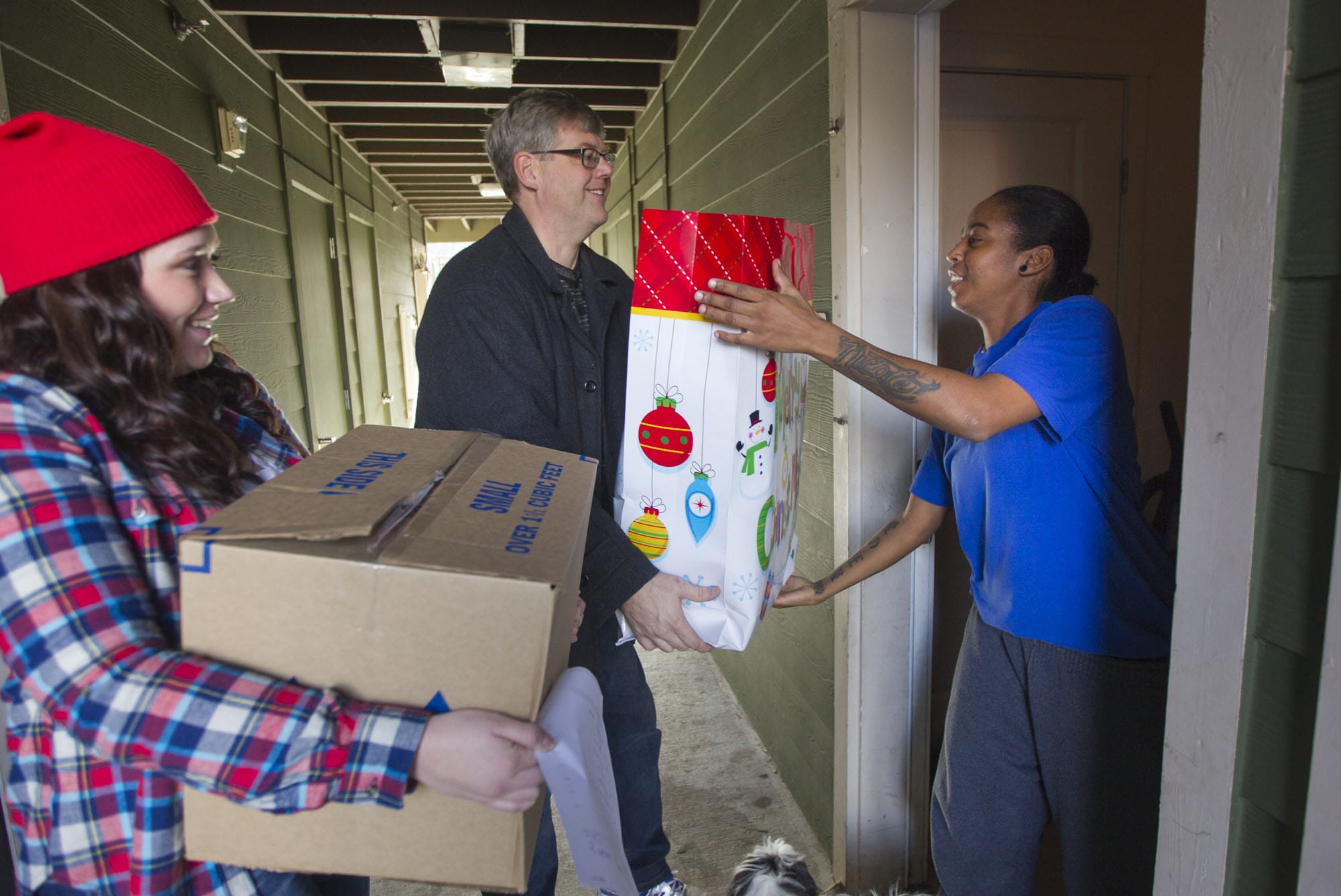 Volunteer Taylor Vossen, from left, and Woodland Rotary Club President Jeff Stay deliver a box of food to Latoya Black on Monday in Woodland.