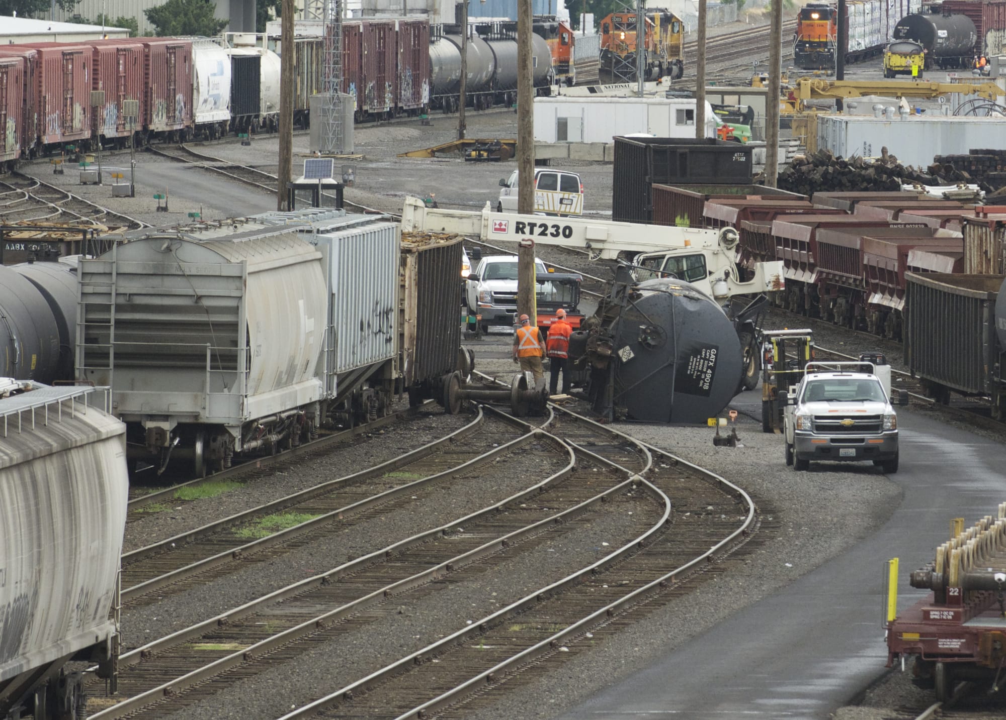 Crews work to flip a derailed tank car containing liquid asphalt in the BNSF Railway Vancouver yard near the Fourth Plain Boulevard overpass on Friday.