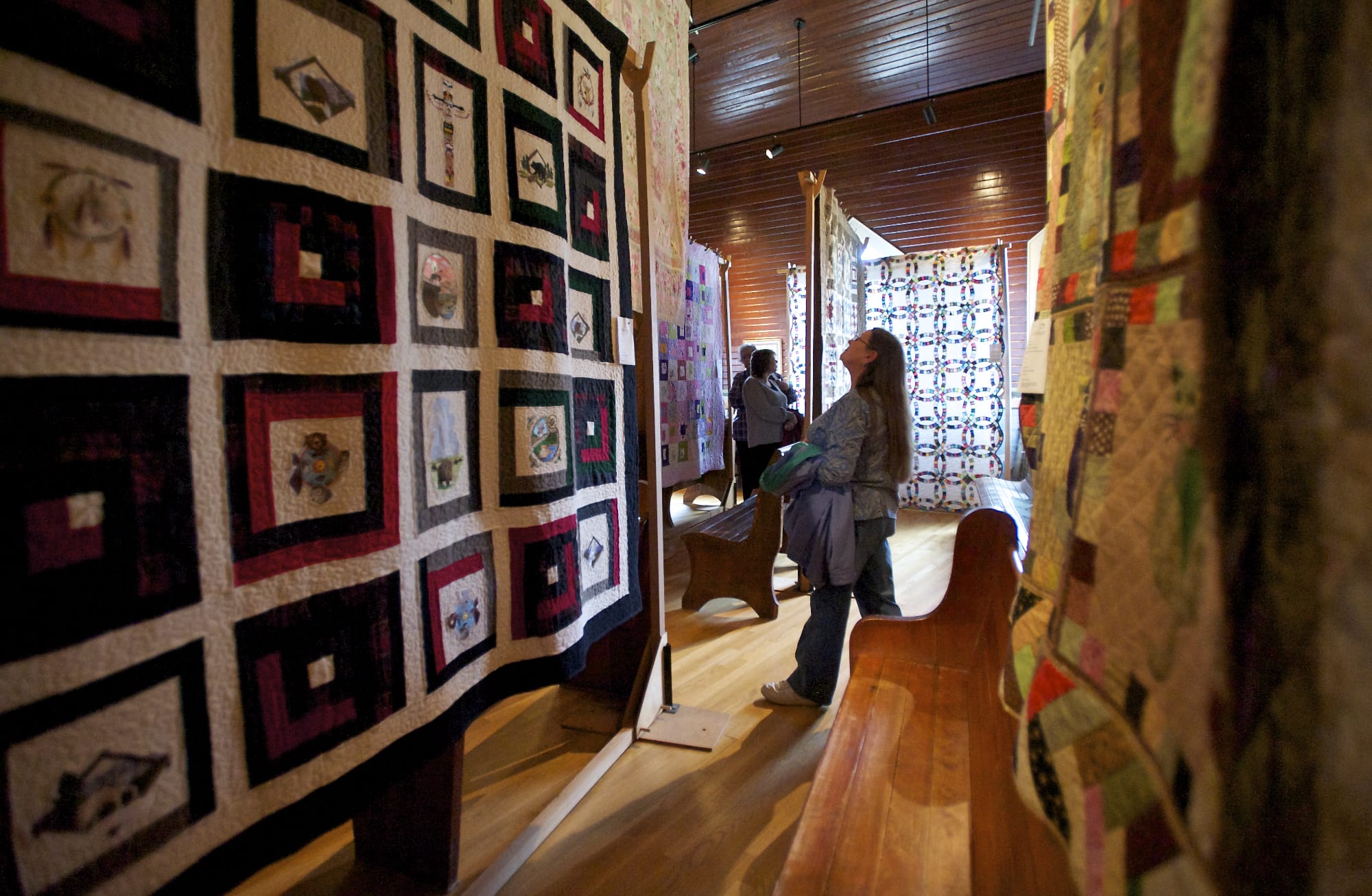 Sewer and crafter Deborah Schmitz of La Center looks up Sunday at a quilt on display at the North Clark Historical Museum in Amboy.