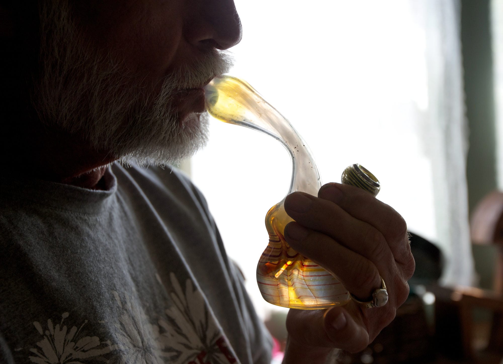 John, a 64-year-old chronic pain sufferer from Camas, smokes marijuana from a water pipe in his home Thursday.