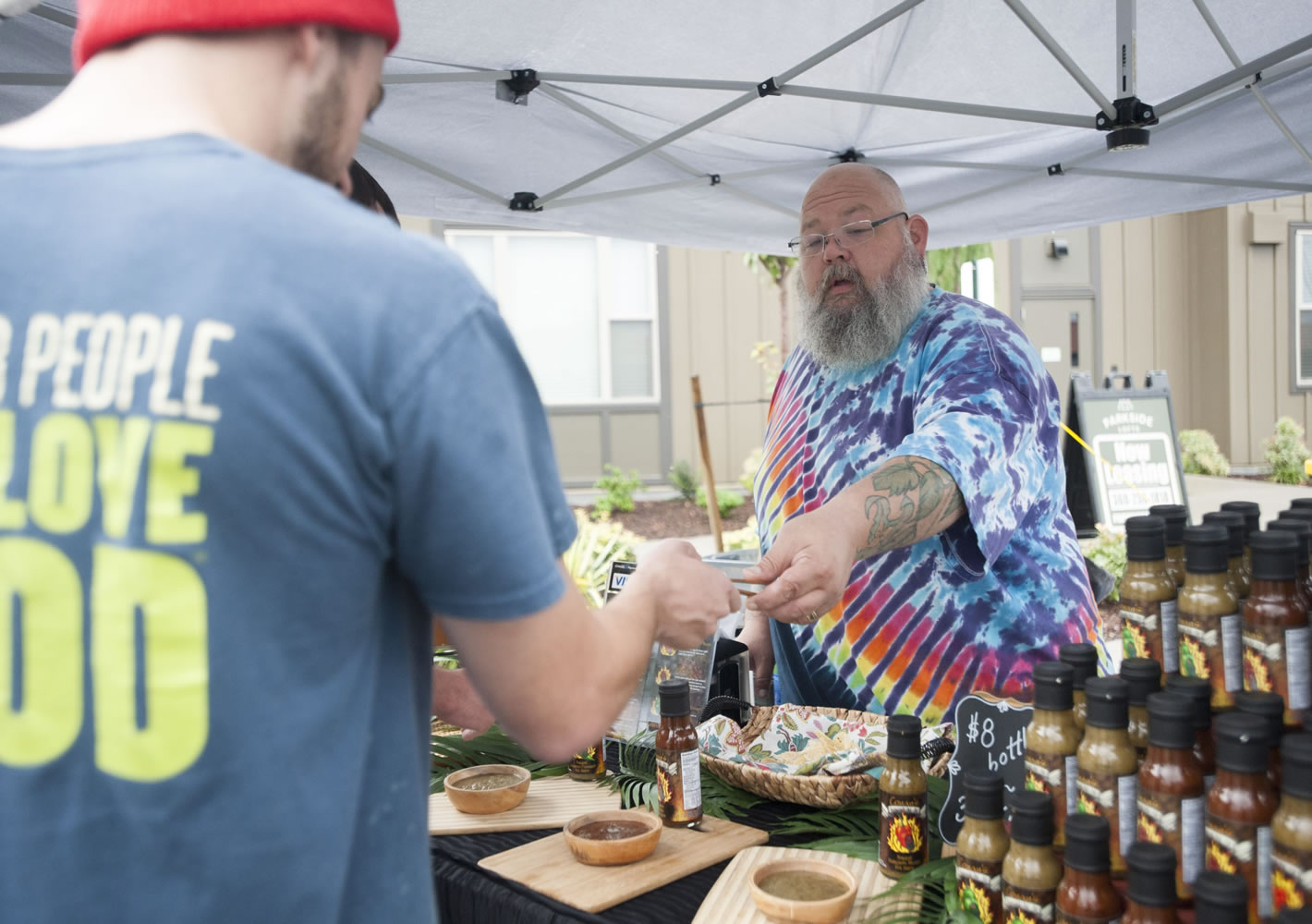 Hot sauce maker Conan Miller gives a customer a sample at his booth at a Farmers Market at Columbia Tech Center in Vancouver on Thursday.