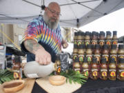 Hot sauce maker Conan Miller prepares samples at his booth at a Farmers Market at Columbia Tech Center in Vancouver on Thursday.