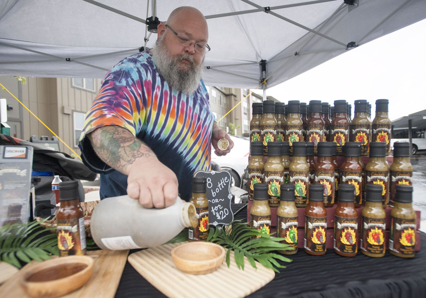 Hot sauce maker Conan Miller prepares samples at his booth at a Farmers Market at Columbia Tech Center in Vancouver on Thursday.