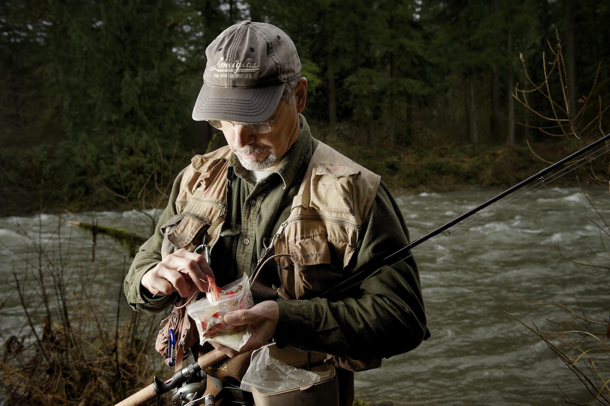 Lyle Cabe sorts through a plastic bag of spinners and spoons looking for the lure he wants while fishing for winter steelhead in the East Fork of the Lewis River.