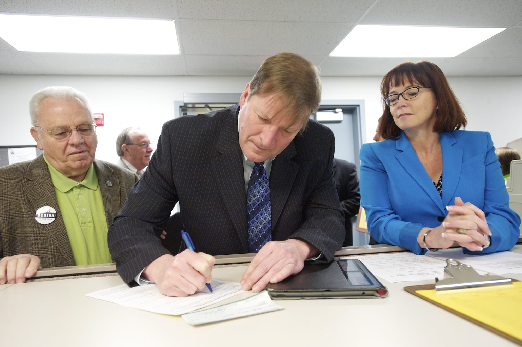 Craig Pridemore, center, files as a candidate for Clark County commissioner at the Clark County Elections Office on Monday as  Ed Barnes, left, and Kelly Love Parker look on.