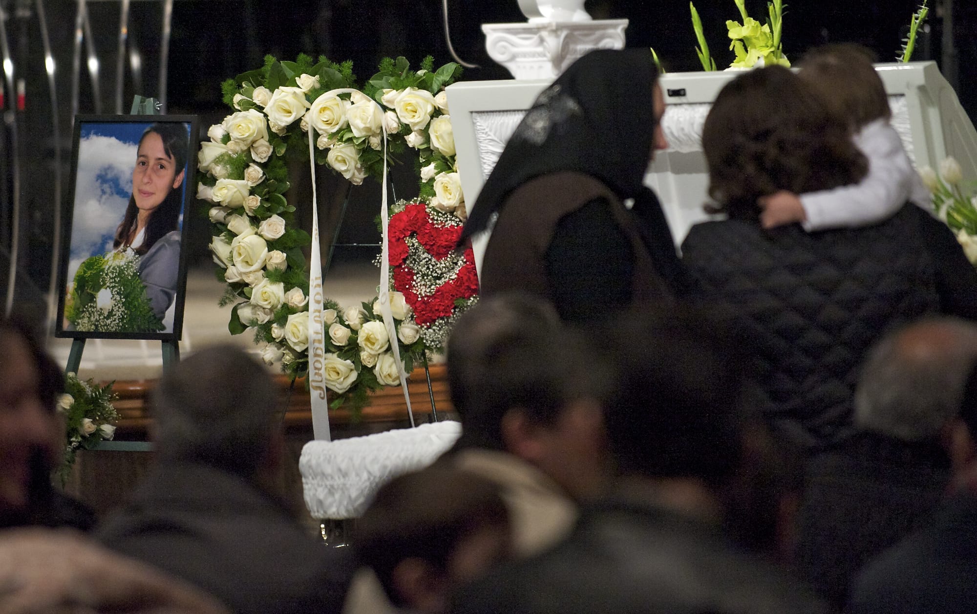 Women look inside Irina Gardinant's casket during the memorial service for her and Raisa Mosh.