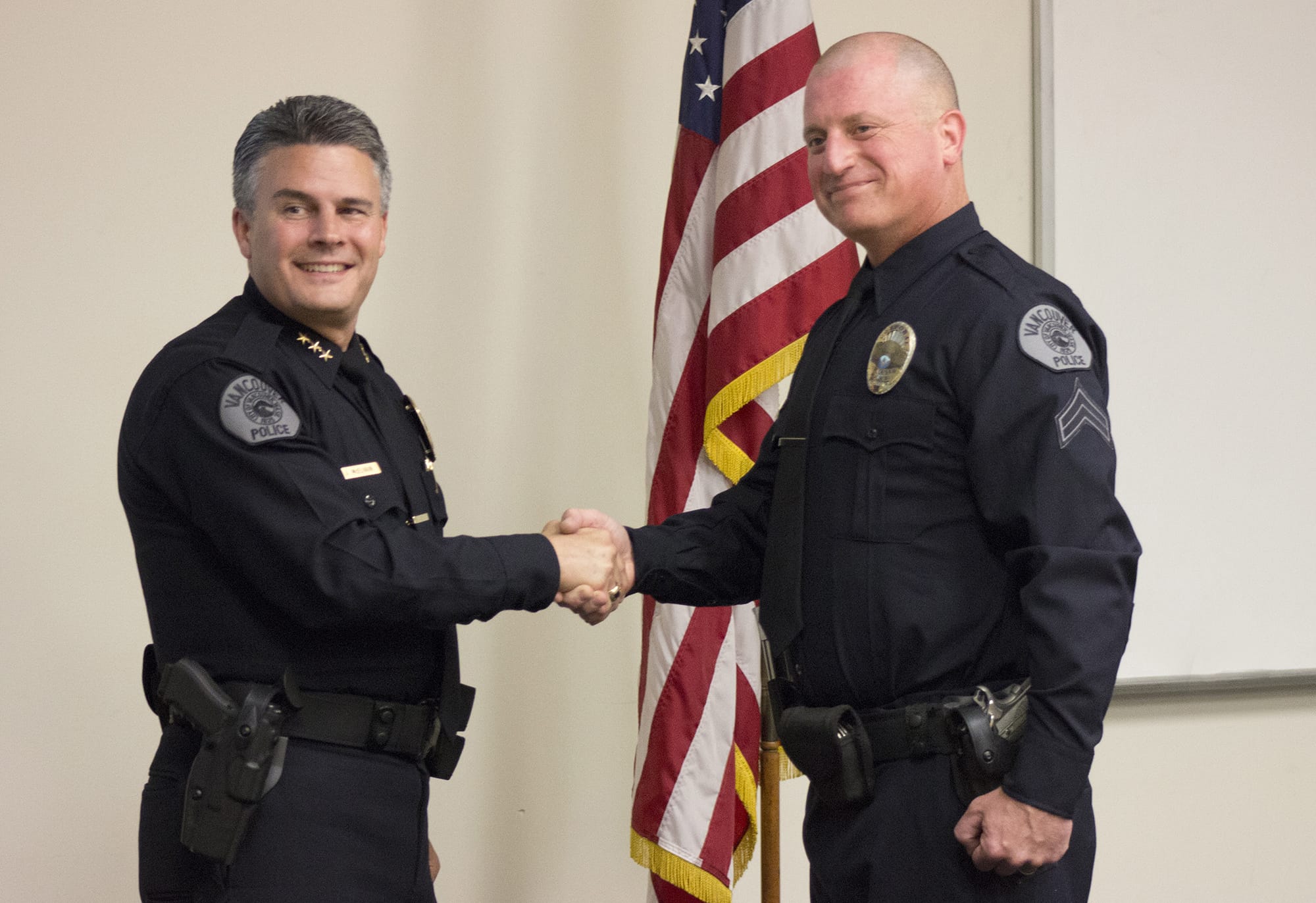Vancouver Police Chief James McElvain, left, and Cpl. Aaron Gibson pose for a picture after Gibson's promotion ceremony Friday at the department's west precinct. Gibson was fired in 1997 for leaving explosives behind at a training site, but won his job back through arbitration.
