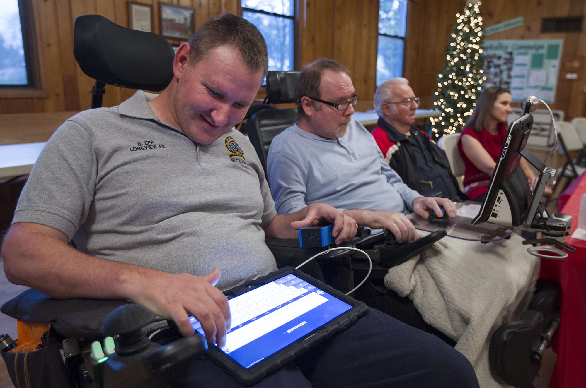 Brian Epp, left, uses a tablet to communicate with John Meyer of Camas at the regional ALS Association support group's Christmas potluck Wednesday at St. Luke's Episcopal Church in Vancouver.