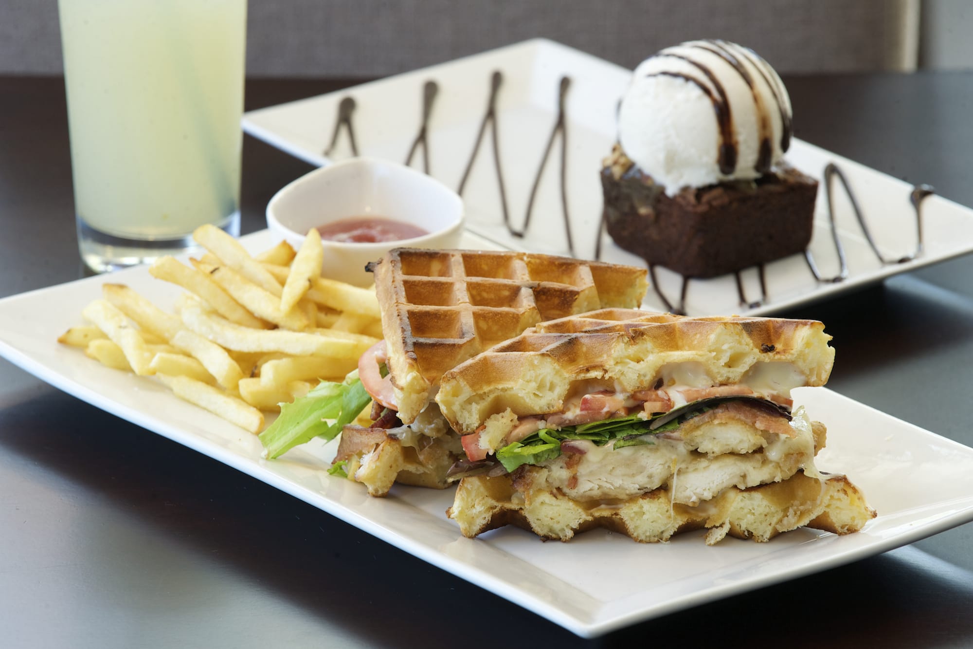 Luxe's chicken and waffle sandwich is stacked with greens, Gruy?re cheese, bacon, tomato and breaded chicken.