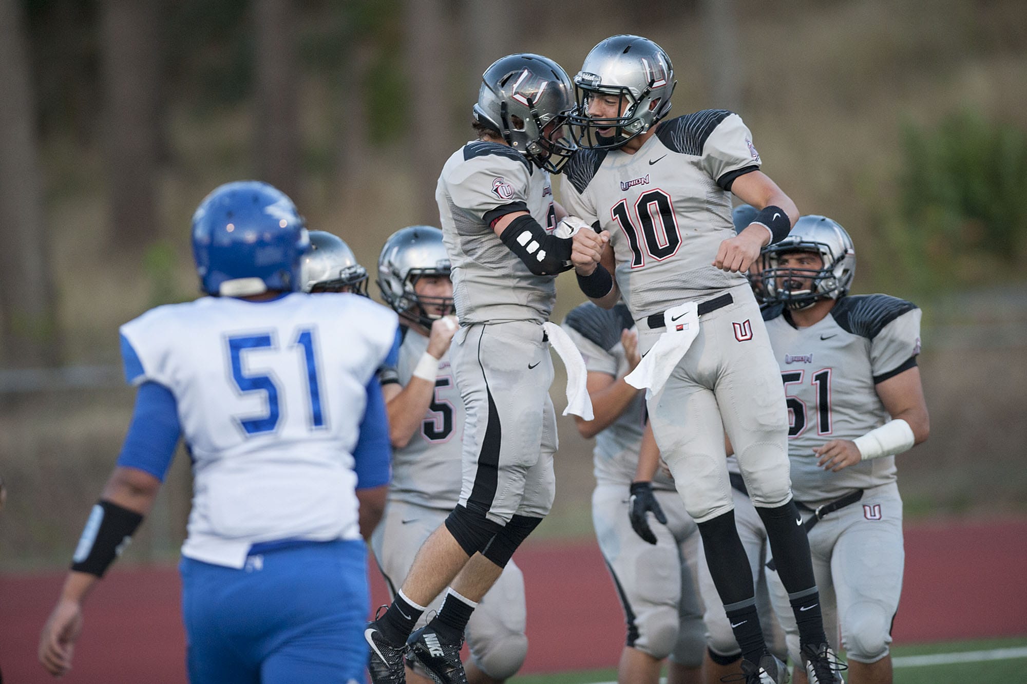 Union High School's Keithen Shepard, center, celebrates with teammates including Jordan Lawson (10) after scoring a touchdown in the first quarter as Federal Way's Oly Leonardo (51) walks past Friday night, Sept.