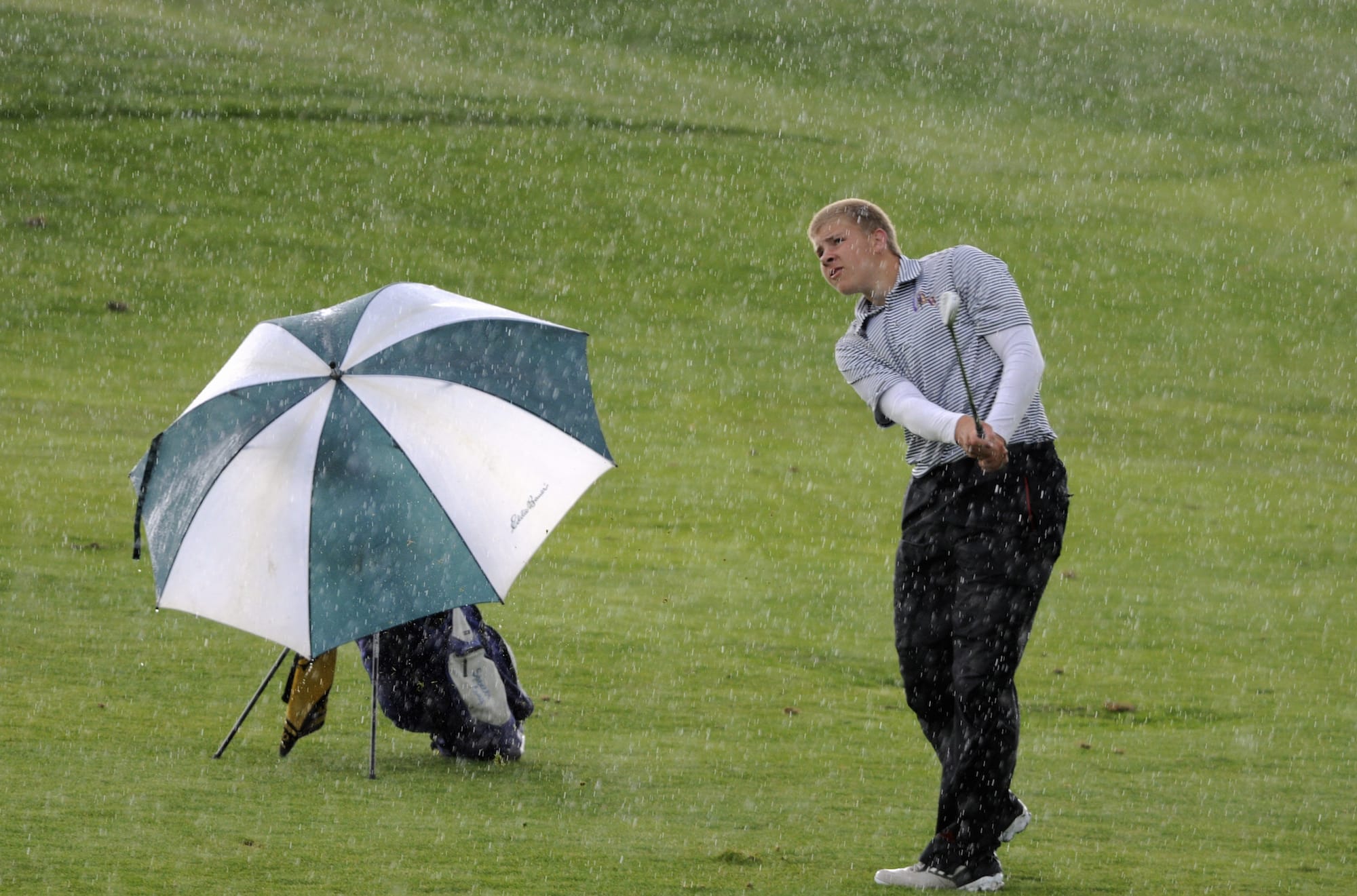 Spencer Long of Columbia River High watches his hit in a downpour as he competes in the 3A boys state golf tournament at the Tri Mountain Golf Course in Ridgefield Wa., Wednesday May 28, 2014.