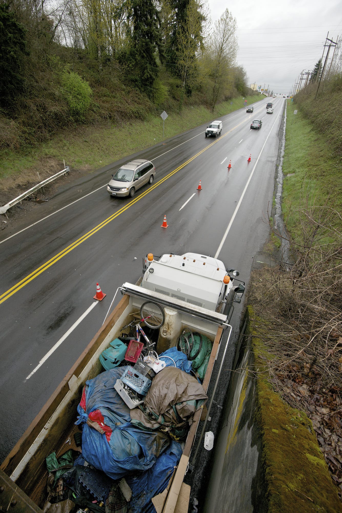 A dump truck parked along Highway 99 is filled with debris from a homeless camp, collected by a Larch Corrections Center crew Wednesday.