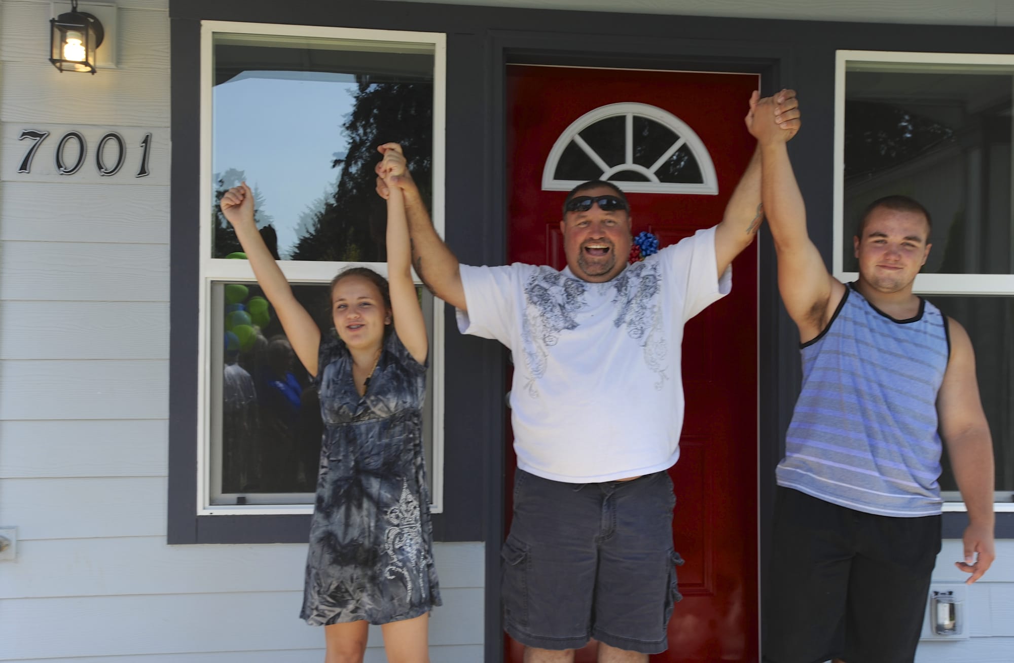 The West family -- daughter Cheyenne, dad Doug, and son Kody -- celebrate on the front porch of their new home Sunday.